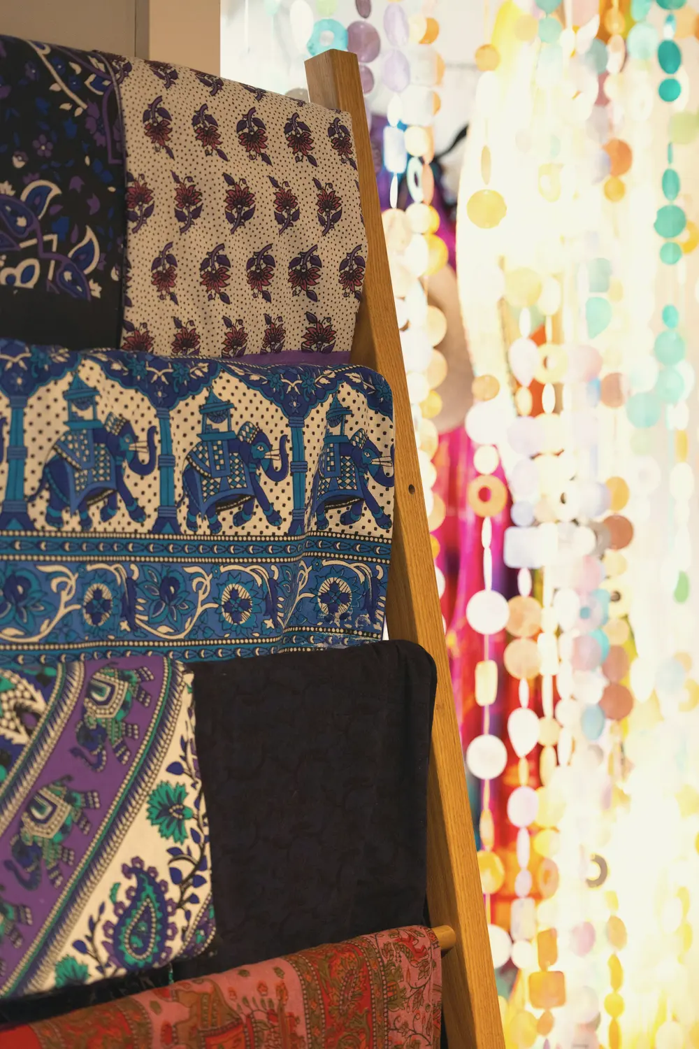 Patterned fabrics hanging over a wooden ladder