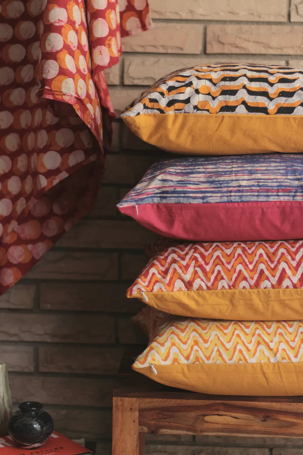 A stack of four patterned cushions in red, blue and saffron