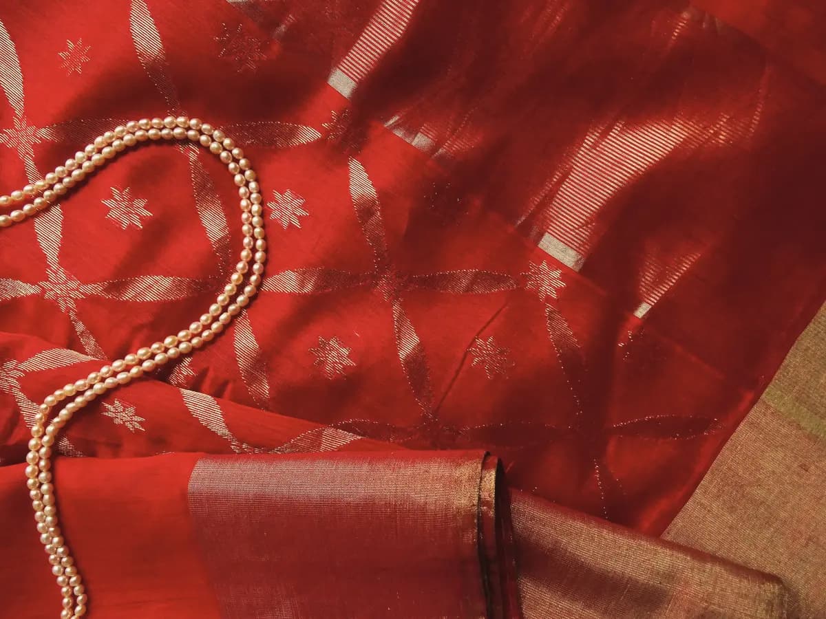 Red silk with small silver motifs, a string of beads resting on it