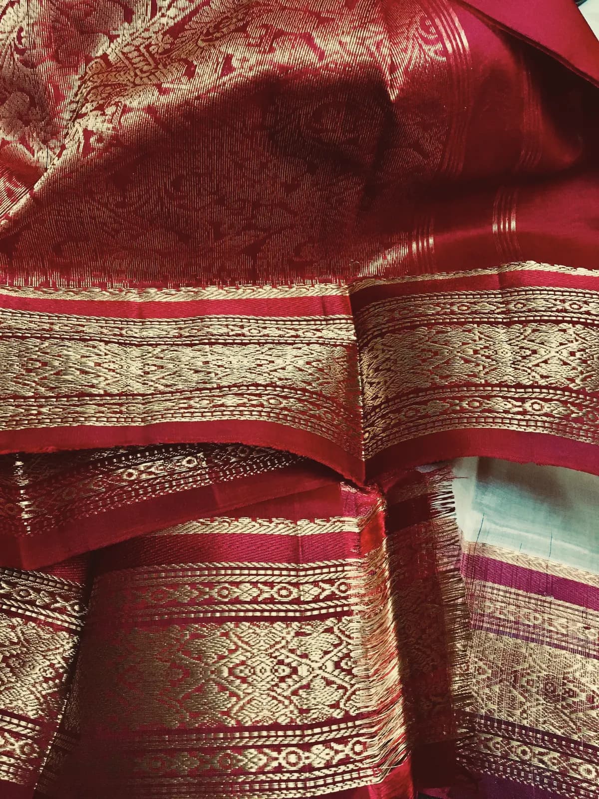 Folds of a deep red silk sari with a broad gold zari border