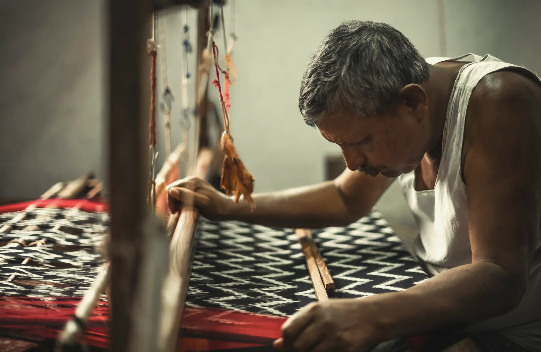 A weaver at his loom, a black and white pattern growing on the cloth