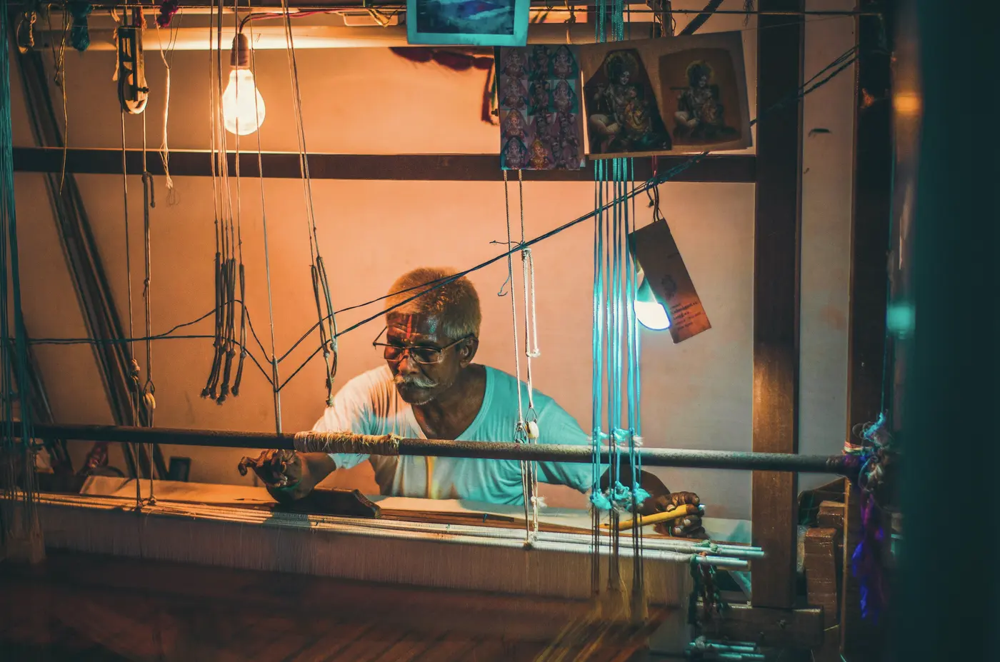 A weaver working at a large loom in warm evening light