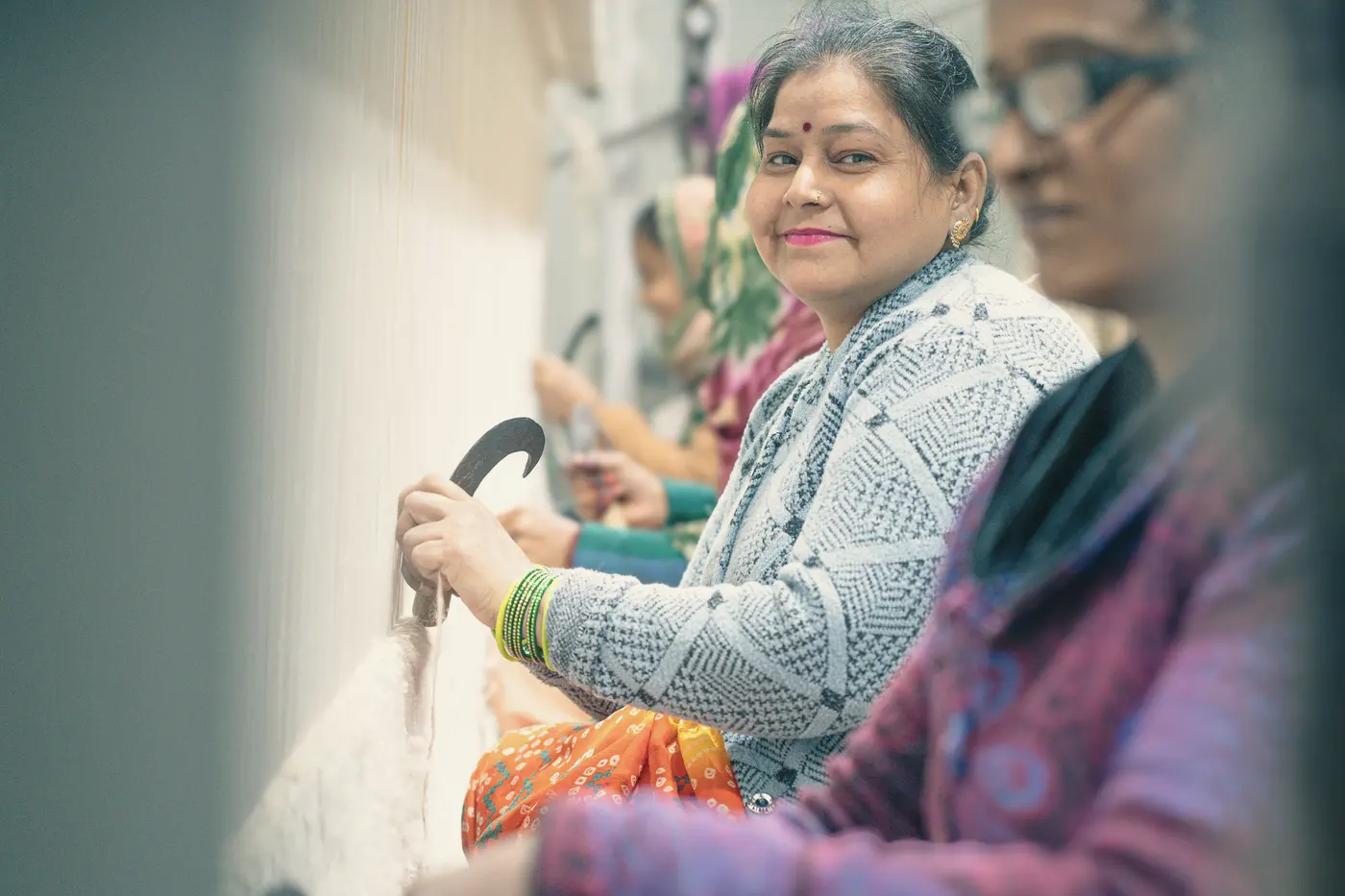 A smiling woman weaver at work with thread in a carpet workshop
